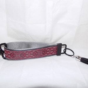 May include: A silver and red patterned key chain with a black tassel and a silver ring.