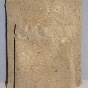 May include: Two beige drawstring pouches with a gold flecked texture. The larger pouch has a zipper closure.