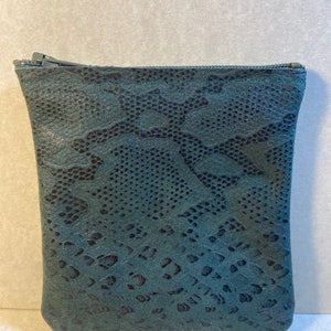 Puede incluir: Una peque&ntilde;a bolsa verde oscuro con cremallera y estampado de piel de serpiente.