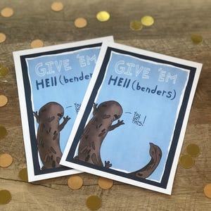 May include: Two greeting cards with the text "GIVE 'EM HELL (benders)" and a cartoon illustration of a brown creature. The cards have a blue background and a white border. The text "You GOT THIS!" is also included.