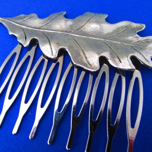 May include: Silver hair comb with an oak leaf design. The comb has seven teeth.