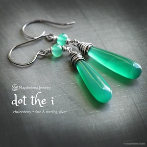 May include: A pair of silver drop earrings with bright green teardrop-shaped chalcedony stones. The earrings have a small green bead at the top and are labeled "dot the i" with "chalcedony • fine & sterling silver".