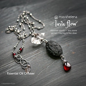 Könnte beinhalten: Eine silberne Halskette mit einem Herkimer-Quarzkristall, Lavastein und einem roten Granat-Anhänger. Die Halskette ist mit "Essential Oil Diffuser" beschriftet und trägt den Text "lava flow".