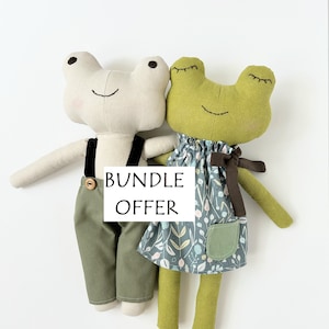 May include: A bundle offer featuring two handmade frog plushies. The frog on the left is wearing green trousers and a black suspender. The frog on the right is wearing a green and blue floral dress with a brown ribbon. The text "BUNDLE OFFER" is written on a white tag.