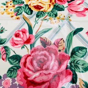 May include: A close-up of a floral pattern featuring large pink roses, yellow and red flowers, and green leaves. The background is white with a subtle blue and white grid design. The overall theme is vintage floral.
