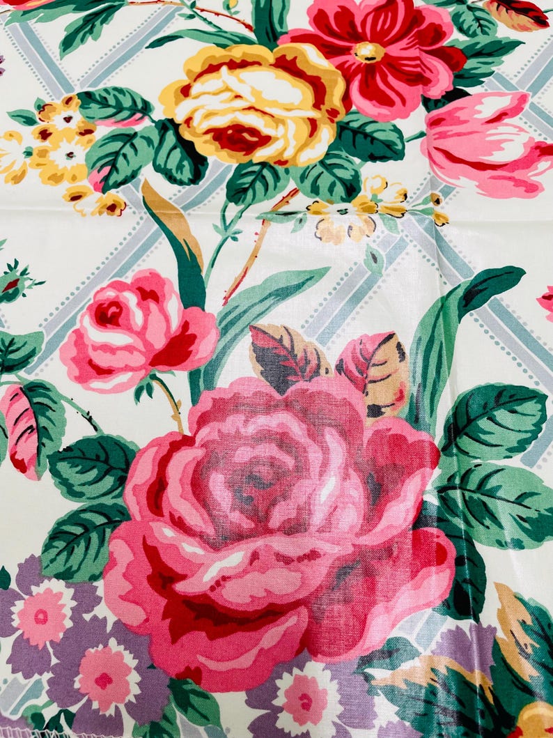 May include: A close-up of a floral pattern featuring large pink roses, yellow and red flowers, and green leaves. The background is white with a subtle blue and white grid design. The overall theme is vintage floral.