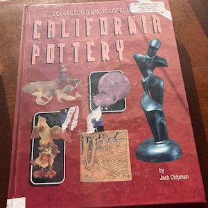 May include: A hardcover book titled "Collector's Encyclopedia California Pottery" with various pottery examples. The cover is maroon with white text and features a black sculpture and several pottery pieces.