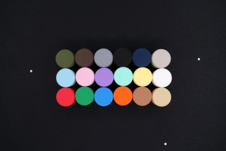 May include: A collection of colorful, round objects arranged in rows on a black surface. The objects are in various colors, including green, brown, gray, black, blue, and white. The image is well-lit and the colors are vibrant.