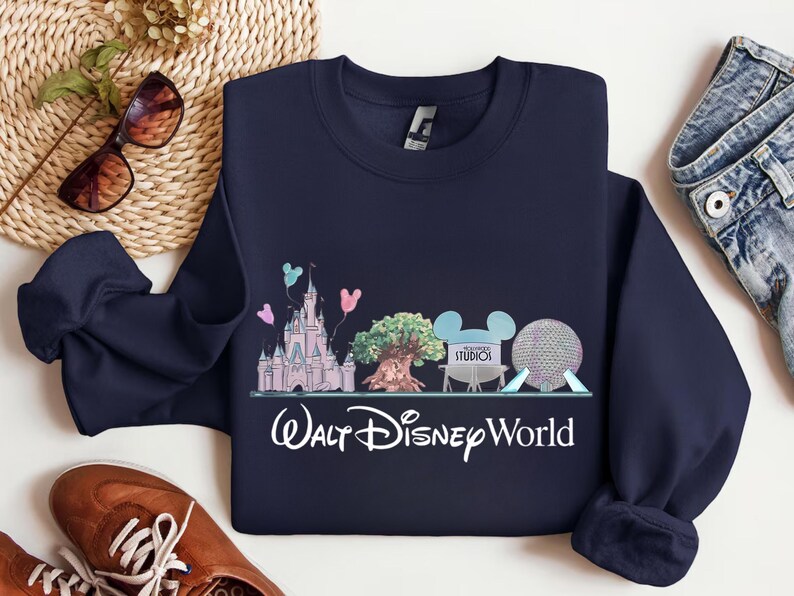 Op de afbeelding: Marineblauw sweatshirt met een kleurrijke afbeelding van Walt Disney World-bezienswaardigheden, waaronder een kasteel, een boom en Spaceship Earth. De woorden "Walt Disney World" staan eronder in witte letters. Een comfortabele, casual top.