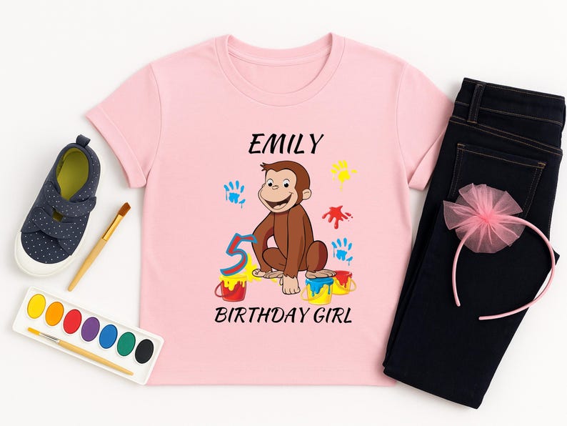 May include: A pink t-shirt with the name "Emily", a cartoon monkey, the number "5", and the words "Birthday Girl". The shirt is paired with dark blue jeans, a pink headband, and navy blue shoes.