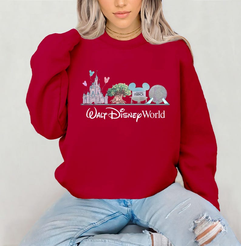 Op de afbeelding: Een rode sweatshirt met een Walt Disney World-ontwerp. De afbeelding toont een kasteel, boom, Mickey Mouse-oren en een bol. De woorden "Walt Disney World" staan eronder in witte letters.