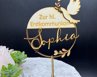 Pode incluir: Topo de bolo de madeira com uma pomba e um círculo que diz "Zur hl. Erstkommunion Sophia".