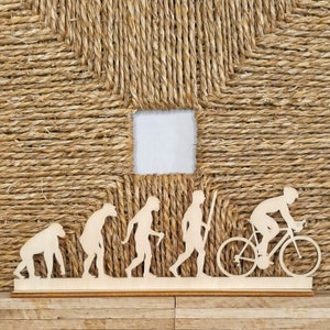 Può includere: Sagoma in legno dell'evoluzione dell'uomo, che termina con una persona in bicicletta. La sagoma è su una base in legno.