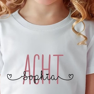 Peut inclure: T-shirt blanc avec le texte "ACHT" en rose et "Sophia" en noir avec un c&oelig;ur de chaque c&ocirc;t&eacute; du nom.
