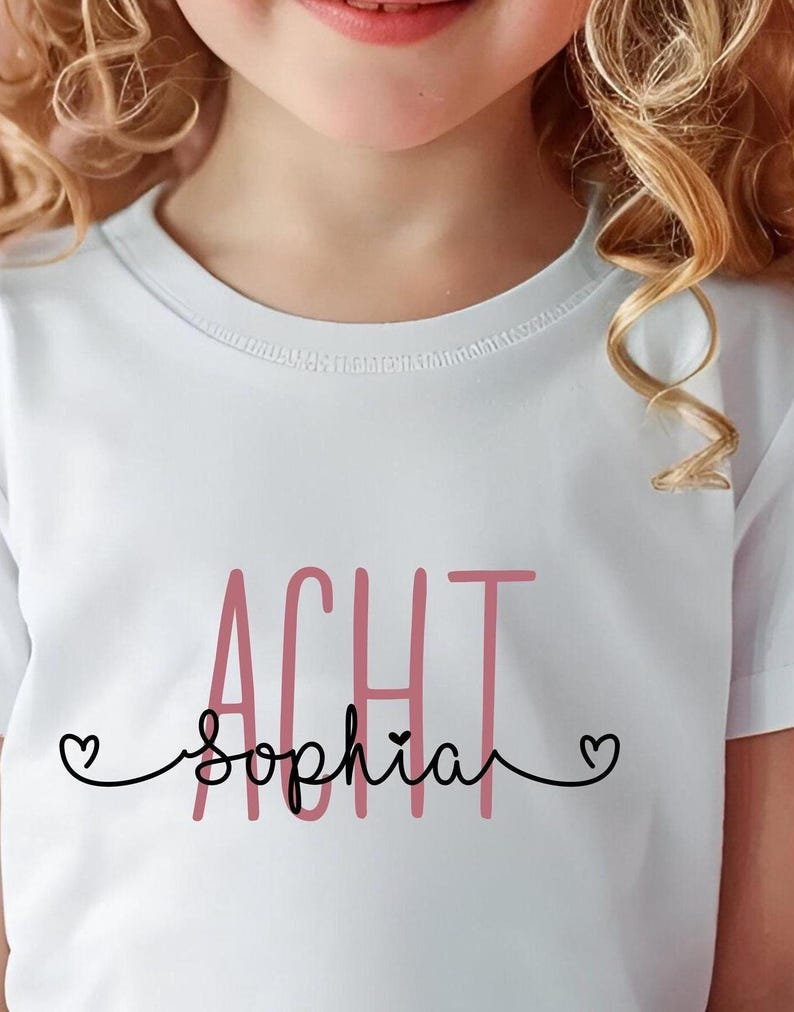 Peut inclure: T-shirt blanc avec le texte "ACHT" en rose et "Sophia" en noir avec un c&oelig;ur de chaque c&ocirc;t&eacute; du nom.