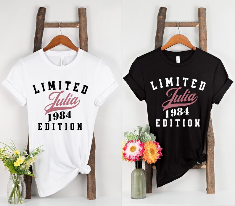 May include: Two t-shirts with a black and white graphic print. The white t-shirt has a pink "Julia 1984" text and the black t-shirt has a white "Limited Julia 1984 Edition" text.