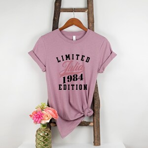 May include: A mauve t-shirt with the text "LIMITED Julia 1984 EDITION" printed on it.