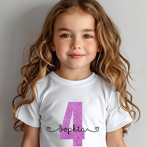 May include: White t-shirt with a pink glittery number 4 and the name "Sophia" written below it.