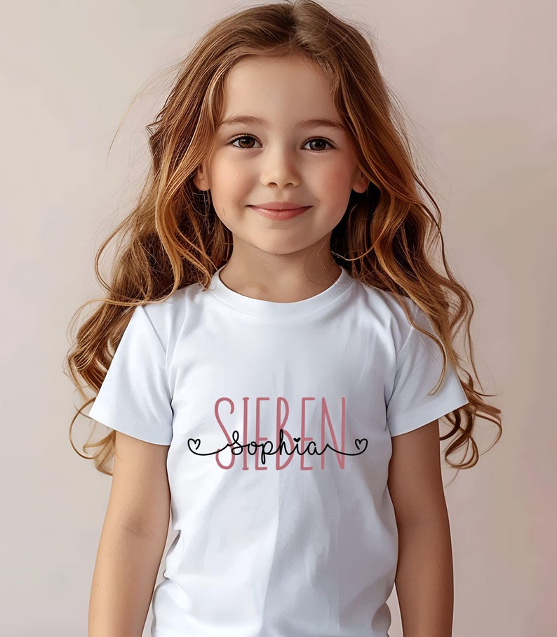 Peut inclure: T-shirt blanc avec le texte "Sieben" en noir et "Sophia" en rose avec des c&oelig;urs de chaque c&ocirc;t&eacute;.