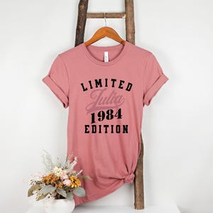 May include: A pink t-shirt with black text that reads "LIMITED Julia 1984 EDITION".