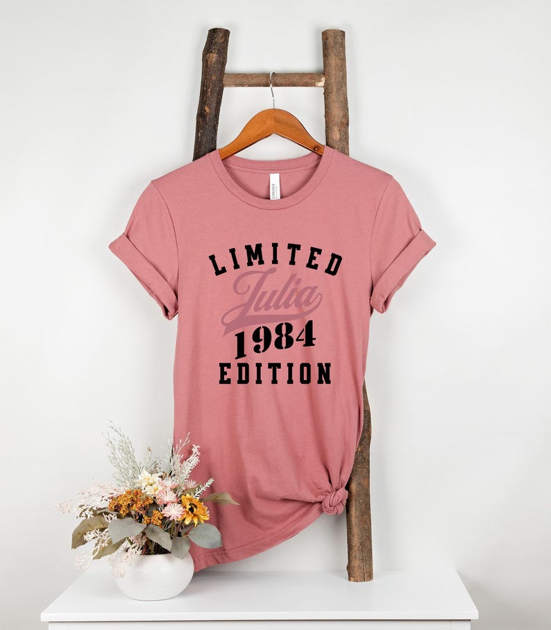May include: A pink t-shirt with black text that reads "LIMITED Julia 1984 EDITION".