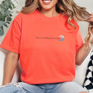 Pu&ograve; includere: Una maglietta arancione brillante con una grafica di un'onda e il testo "There's no telling how far I'll go".