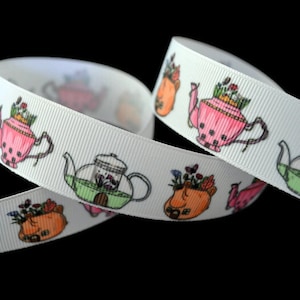May include: White ribbon with a repeating pattern of teapots with flowers. The teapots are in various colors, including pink, green, and orange.