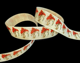 May include: Off-white ribbon with a repeating pattern of red mushroom figures wearing Christmas lights. The ribbon is curled and displayed against a black background. The mushrooms have red caps and are decorated with colorful lights.