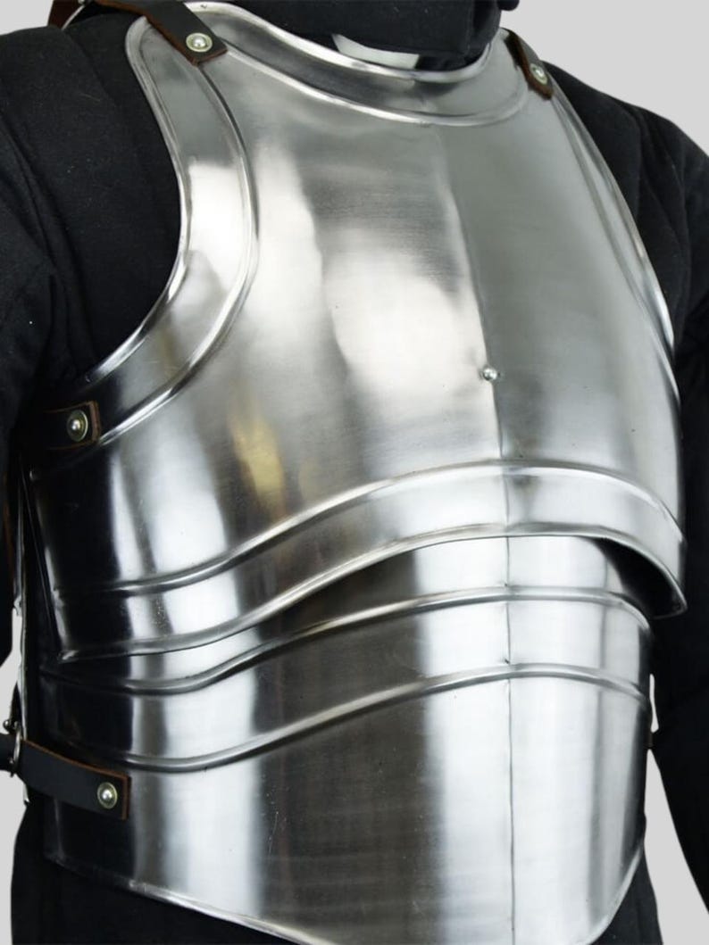 May include: A polished steel breastplate, offering torso protection.  The medieval-style armor features a curved, segmented design with visible rivets and straps.  The smooth, reflective surface shows highlights.  This piece of body armor is suitable for historical reenactment or costume.