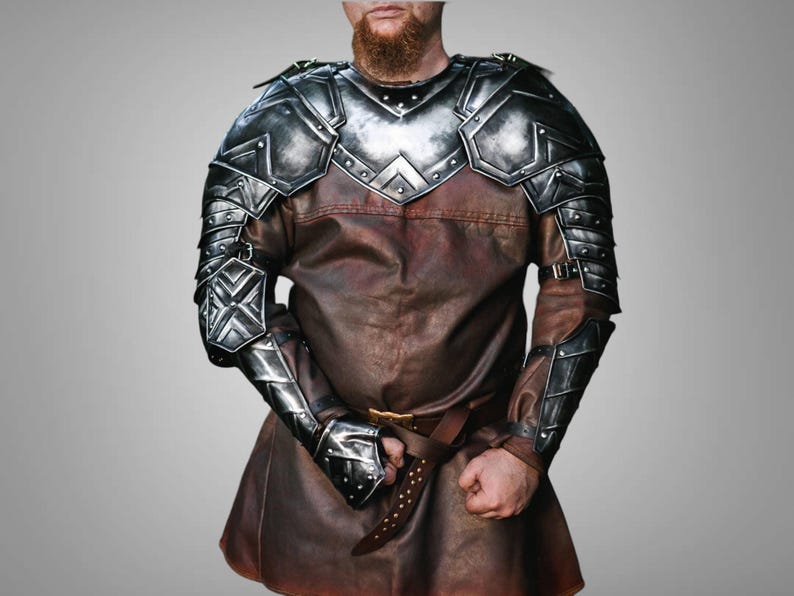 May include: Silver and black metal armor for the arms and shoulders. The armor is made of metal plates and has a medieval design.