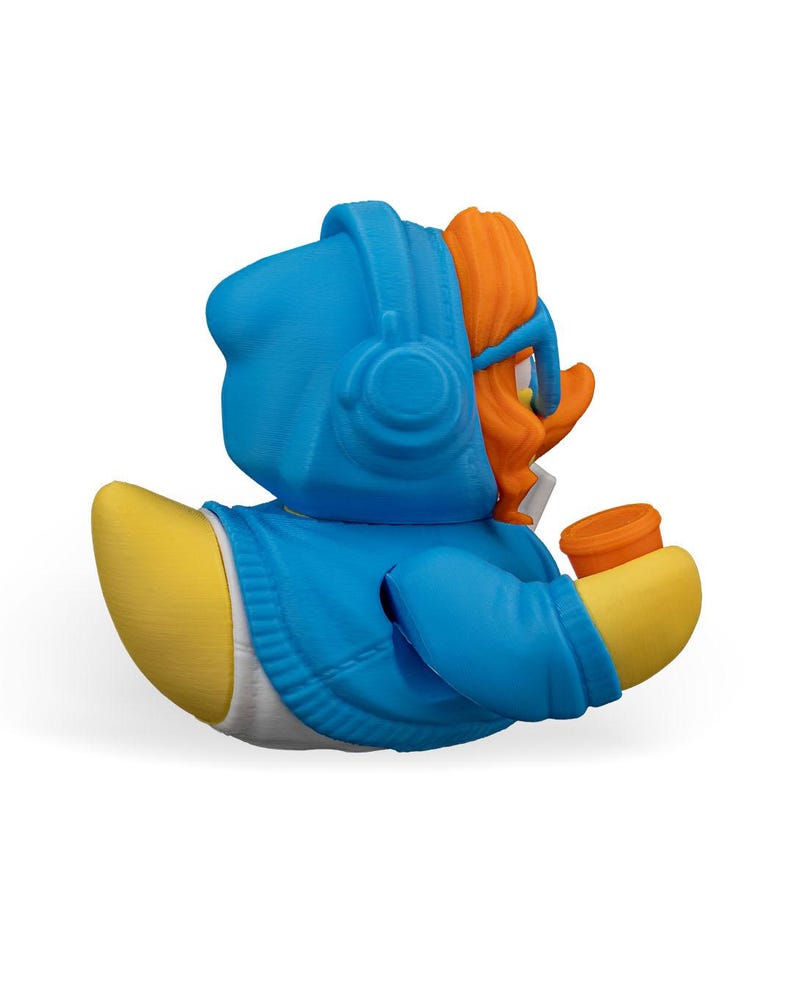May include: A blue rubber duck wearing a blue hoodie with a white zipper and orange hair. The duck is holding a small orange cup in its right hand.