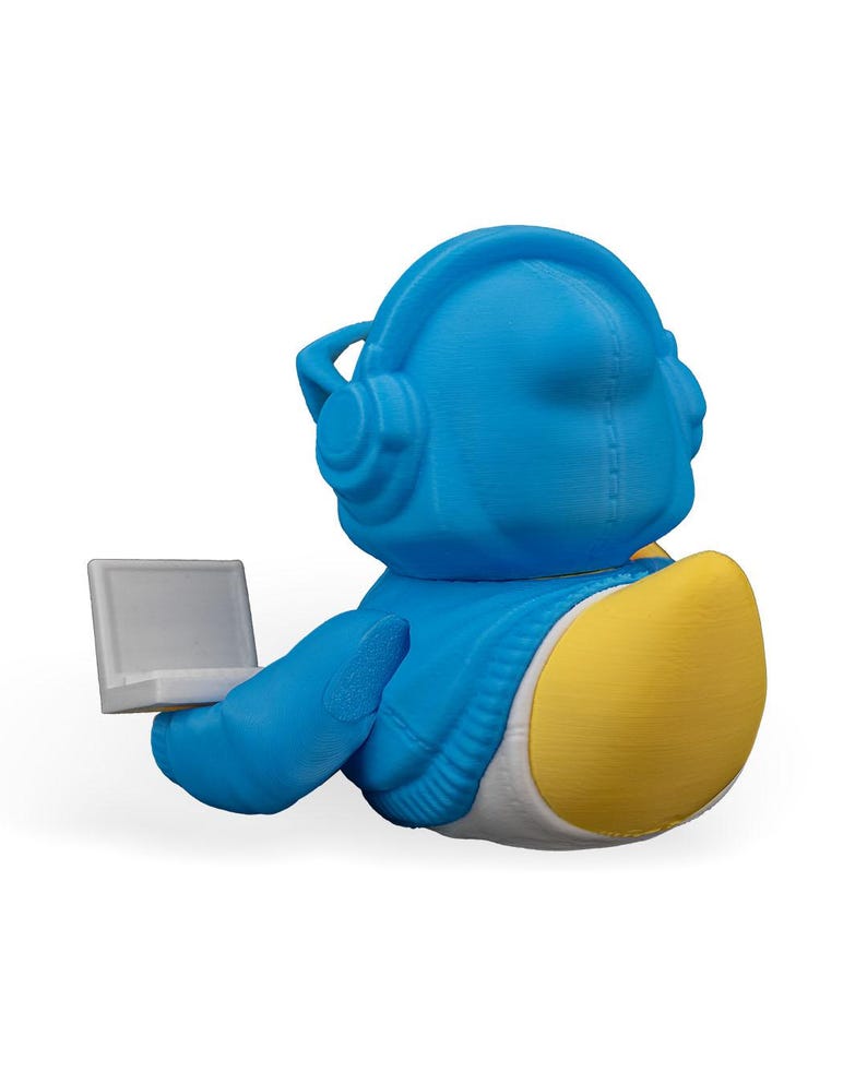 May include: A blue and yellow 3D printed duck wearing headphones and holding a laptop.