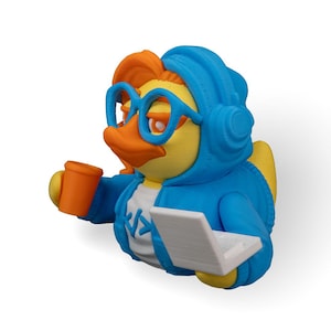 May include: A yellow rubber duck wearing a blue hoodie, headphones, and glasses, holding a cup and a laptop.