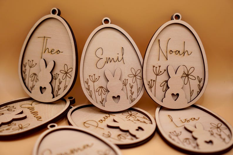 Peut inclure: Ornements d'&oelig;ufs de P&acirc;ques en bois avec des silhouettes de lapins et des noms personnalis&eacute;s, notamment Theo, Emil, Noah, Emma, Paul, Lisa et Carmen.