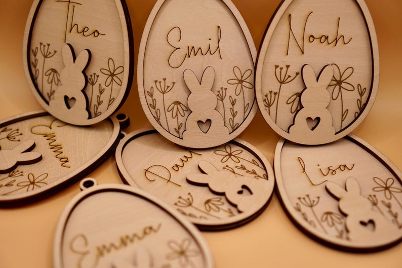 Peut inclure: Huit d&eacute;corations d'&oelig;ufs de P&acirc;ques en bois avec des d&eacute;coupes de lapin et des noms personnalis&eacute;s&nbsp;: Th&eacute;o, Emma, Emil, No&eacute;, Paul, Lisa et deux d&eacute;corations Emma. Les d&eacute;corations sont peintes dans une couleur bois clair et pr&eacute;sentent un motif floral d&eacute;licat.