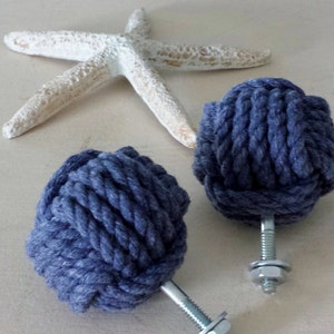 May include: Two dark blue rope drawer pulls with silver metal hardware. The rope is tied in a knot and the hardware is a screw and a nut.