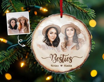 May include: A wooden Christmas ornament featuring two women in hats, with the word "Besties" and names below. A smaller image of the women is in the upper left corner. The ornament hangs from a red ribbon.