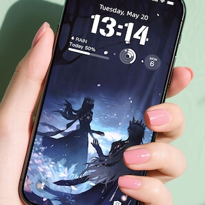 Peut inclure: Un smartphone noir affichant un fond d'écran numérique avec deux silhouettes couronnées. L'écran indique l'heure 13h14, la date et les informations météorologiques. Le téléphone est tenu par une personne avec du vernis à ongles rose.