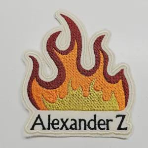 Peut inclure: &Eacute;cusson brod&eacute; en forme de flamme, avec des nuances de rouge, d'orange et de jaune. Le patch a une bordure blanche et le nom "Alexander Z" est brod&eacute; en lettres noires en bas.