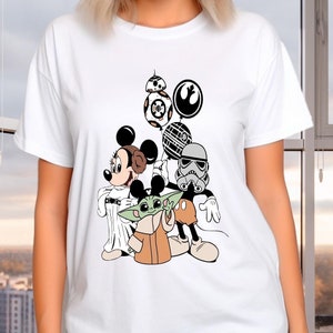 May include: White t-shirt with a graphic print of Mickey Mouse, Yoda, and a Stormtrooper from Star Wars. The characters are holding balloons with the Star Wars logo and the Death Star.