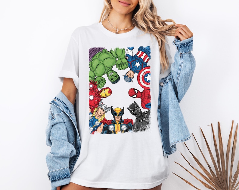 A woman wearing a white t-shirt with a graphic of various Marvel superheroes, including Hulk, Captain America, Iron Man, Spider-Man, and others, arranged in a circular pattern.