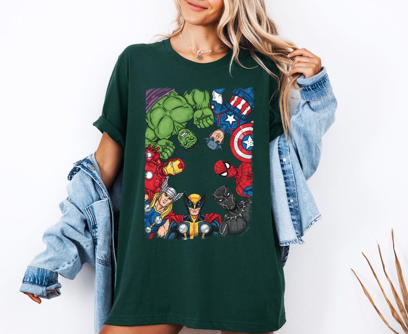 A woman wearing a green t-shirt with a graphic of various Marvel superheroes, including Hulk, Spider-Man, Captain America, and others, standing together.