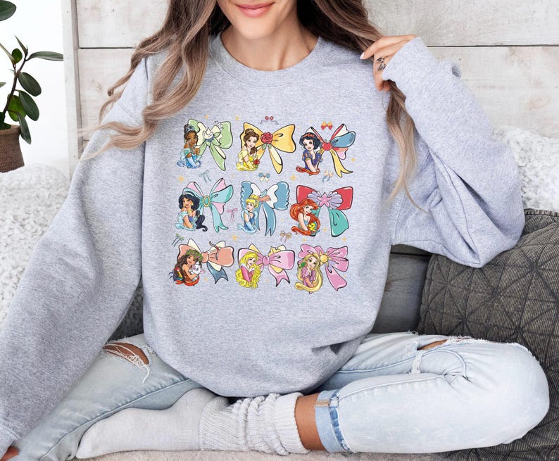 a woman sitting on a couch wearing a sweatshirt with cartoon characters on it