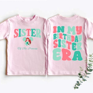 two pink shirts with green and pink letters on them