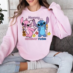 a woman sitting on a couch wearing a pink sweatshirt