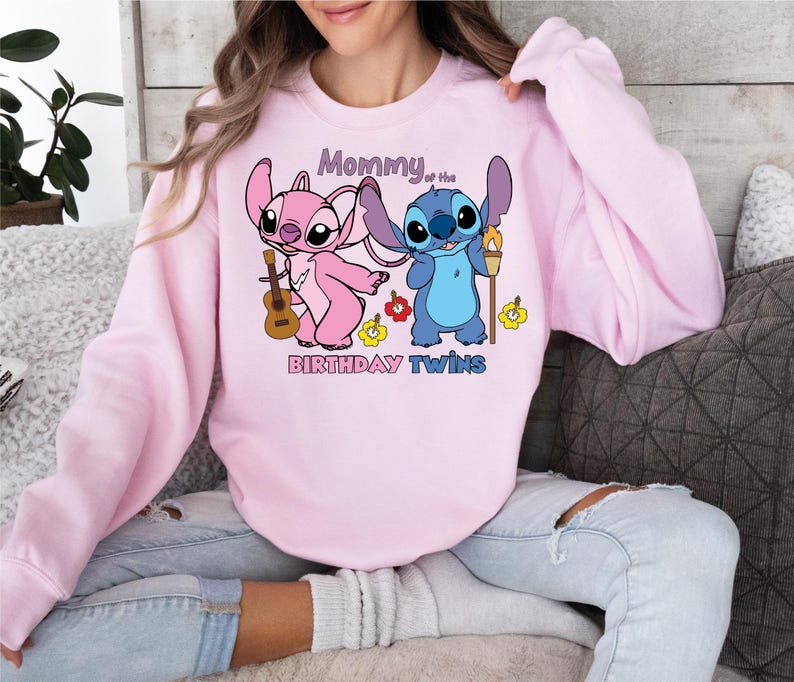 a woman sitting on a couch wearing a pink sweatshirt