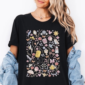 May include: Black t-shirt with a colorful floral design and the text "Best Day Ever." The design includes various illustrations such as a mirror, a carriage, a rose, and butterflies. The shirt is made of a soft material.