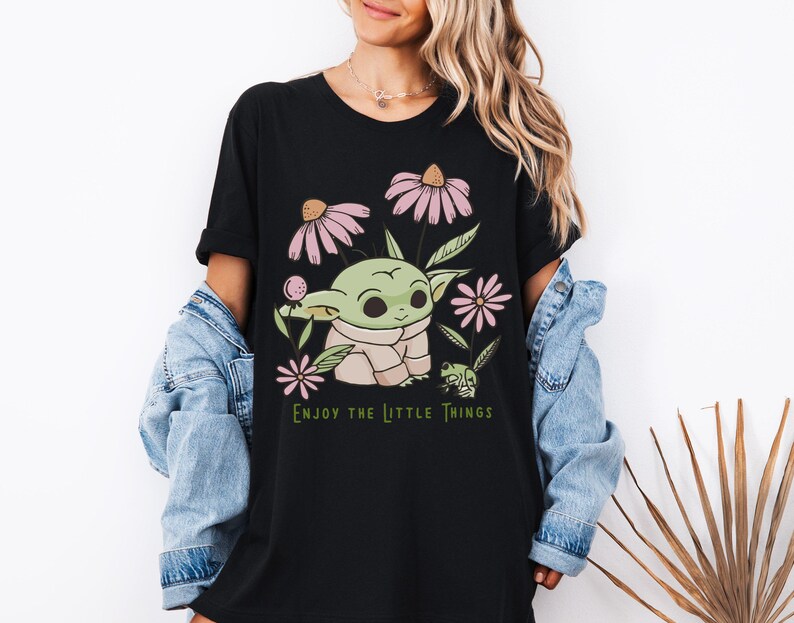 a woman wearing a black t - shirt with a picture of a baby yoda