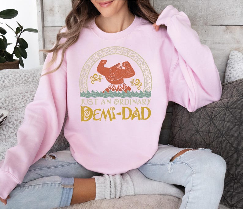 a woman sitting on a couch wearing a pink sweatshirt