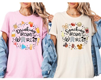 May include: Two pink and beige t-shirts with a graphic design of a circle with various images and the text "Drinking Around the World" and "Snacking Around the World".